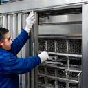 An engineer servicing a stainless steel seafood processing machine.